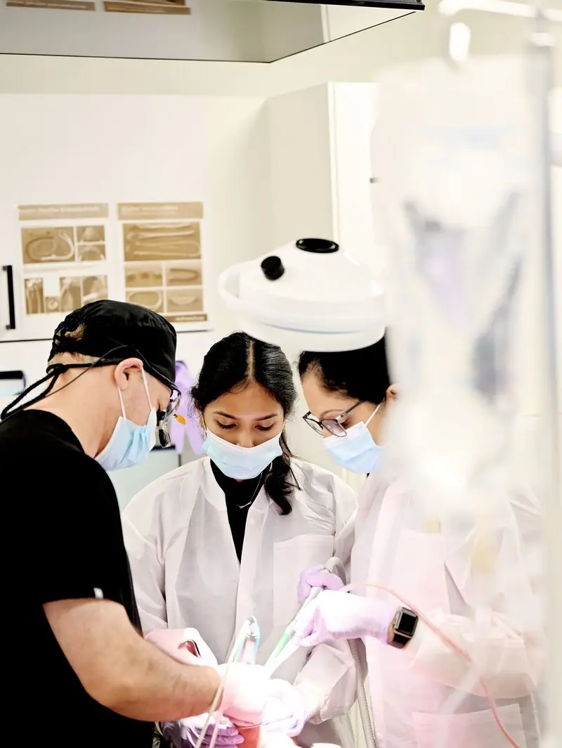 Dental professionals performing a procedure in a modern clinic, wearing masks and gloves.